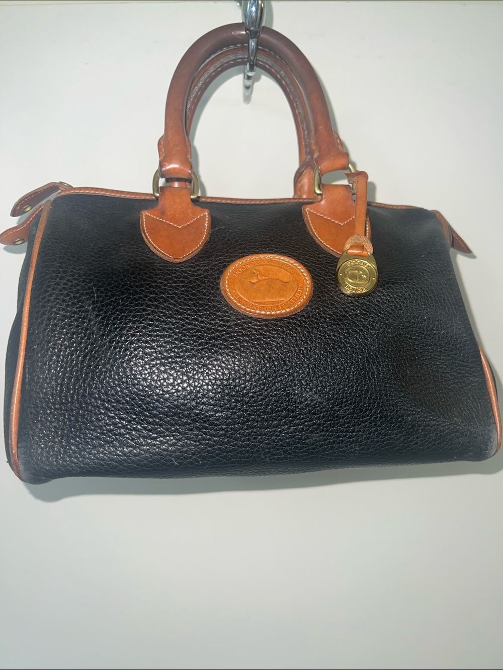 Vintage Dooney &  Bourke black, pebbled, leather satchel. Brown and gold trim.